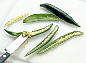 Peppers cut in half and seeded with knife on white surface