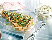 Salmon trout with herb and walnut paste and mushroom sauce in glass serving dish