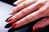 Close-up of woman applying red base coat her fingernails, step 3