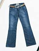 Close-up of blue jeans with belt on white background