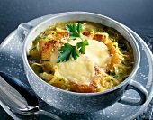 Bowl of baked onion soup with white wine garnished with coriander