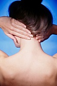 Rear view of woman massaging her neck