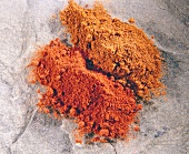 Two heaps of paprika on stone, overhead view