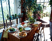 reichlich gedeckter Tisch, draußen sommerlich grüne Natur