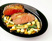 Roast beef with coriander crust with peppercorns and vegetables on plate