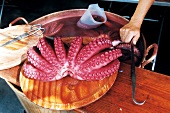 Octopus on wooden chopping board being prepared for consumption