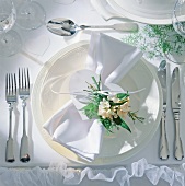 White napkin wrapped with heart shaped card and small bouquet on plate