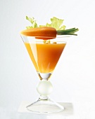 Glass of carrot juice with a carrot and celery on glass edge