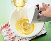 Mixing eggs and oil in bowl with hand whisk for preparation of mayonnaise
