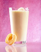 Halved apricot with glass of apricot and mango juice garnished with mandarineneis