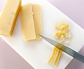 Almond paste being cut into small cubes on white chopping board