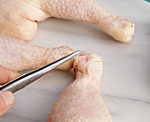 Close-up of feathers being plucked with tweezers from chicken legs