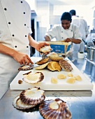Chef detaching scallops from shell
