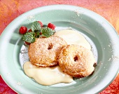 Apple rings in batter with zabaglione sauce powdered sugar and raspberries on plate