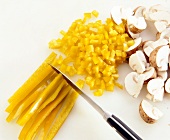 Mushrooms and yellow pepper being diced with kitchen knife