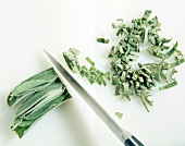 Sage leaves being finely chopped on chopping board