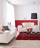 Wohnzimmer mit rotem Teppich und weissen Sofas, schwarze Accessoires