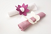 Two rolled napkins tied with napkin rings made from felt