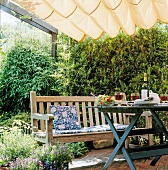 Table with bench and cushion under pergola in garden