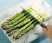Asparagus being chopped into equal pieces on chopping board