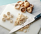 Finely chopped mushroom stems with heads kept aside on chopping board