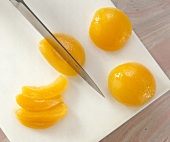 Apricot being cut into slices on chopping board