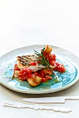 Grilled sea bass with tomato salsa and a sprig of rosemary on plate