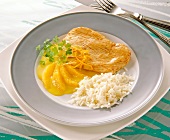 Turkey schnitzel with rice and orange sauce on plate