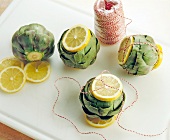 Artichokes being prepared by tying sliced lemons together with yarn