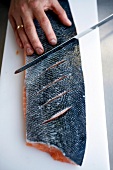 Person cutting the skin of salmon with knifeÃƒÆ’Ã¢â‚¬Å¡Ãƒâ€šÃ‚Â for dressing
