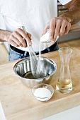Adding sugar to rice vinegar in bowl and mixing with whisk