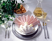 Pastel folded napkin with large shell and cutlery on plate