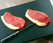 Steak with knife on chopping board for steak with beans