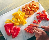 Various vegetables sliced with knife on cutting board, overhead view