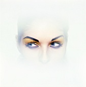Close-up of woman's thoughtful eyes looking away wearing yellow eye shadow