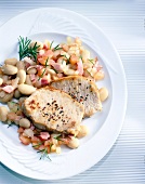 Pork chops with white beans, onions, bacon and rosemary on plate