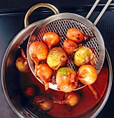 Cooked shallots removed with sieve out of cooking pot, overhead view