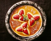 Strawberry gratin with flaked almonds, mint and powdered sugar, overhead view