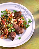 Turkey liver on lentils and tomatoes on plate