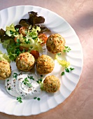 Deep-fried rice balls with salad and yoghurt dip on plate