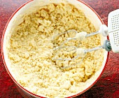 Crumbly dough being mixed with mixer in bowl