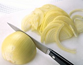 Half onion being cut into thin slices with kitchen knife