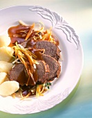 Braised beef with potato dumplings, vegetables and sauce in dish