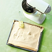 Lemon cream being spread in baking tray having butter paper in it