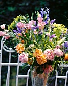 Sommerblumenstrauß in Glasvase auf Gartentisch, Mohn, Rosen, Ranunkeln