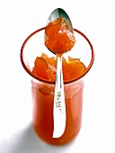 Glass of orange jelly with spoon on it