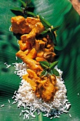 Curry, gelbes Hühnercurry mit Reis und Minze auf einem Blatt
