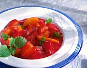 Rote Grütze mit Erdbeeren und Pfirsichen, garniert mit Melisse.