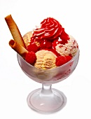 Four scoops of ice cream with raspberries, cream and wafer rolls in ice cream bowl