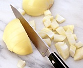 Close-up of onion being cut coarsely with knife
